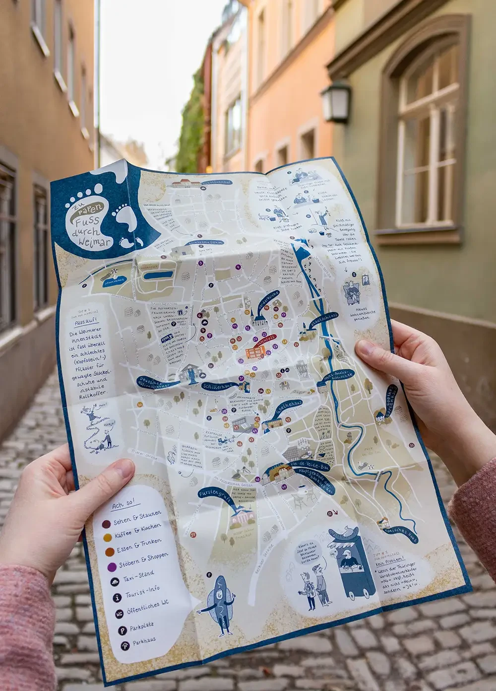 Aufgeklappter Stadtplan vor einer Stadtkulisse.