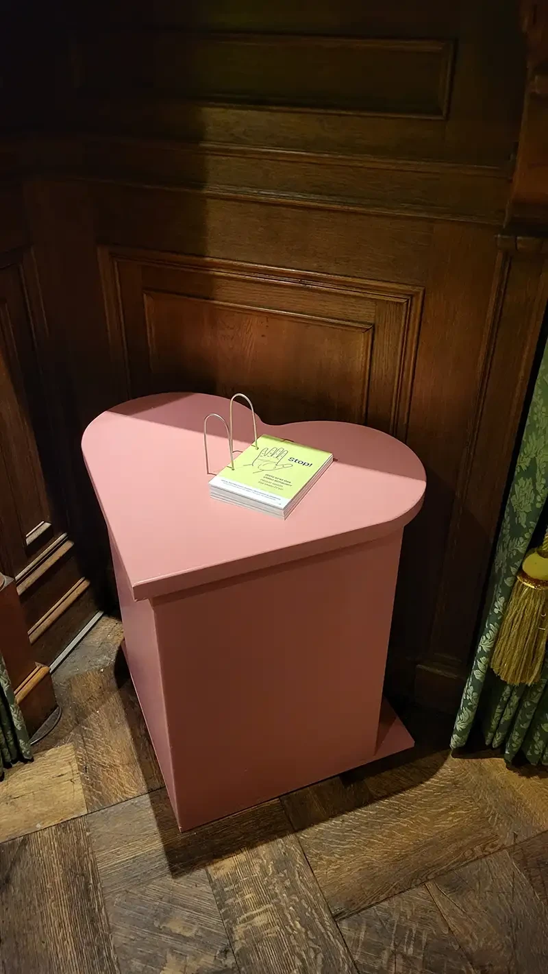 Ein kleiner, rosafarbener Tisch in Herzform. Auf dem Tisch ist ein Buch befestigt.