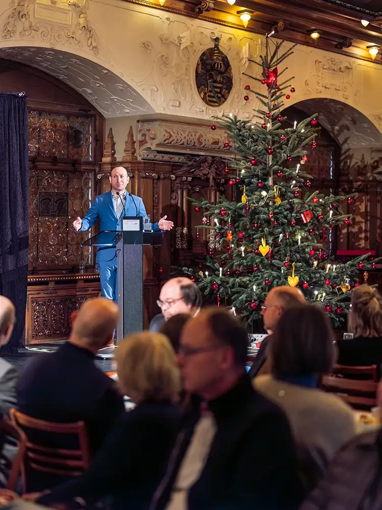Im Bachsaal des Schlosses steht Kurator Toni Krause an einem Rednerpult und hält seine Eröffnungsrede zur Ausstellungseröffnung. 