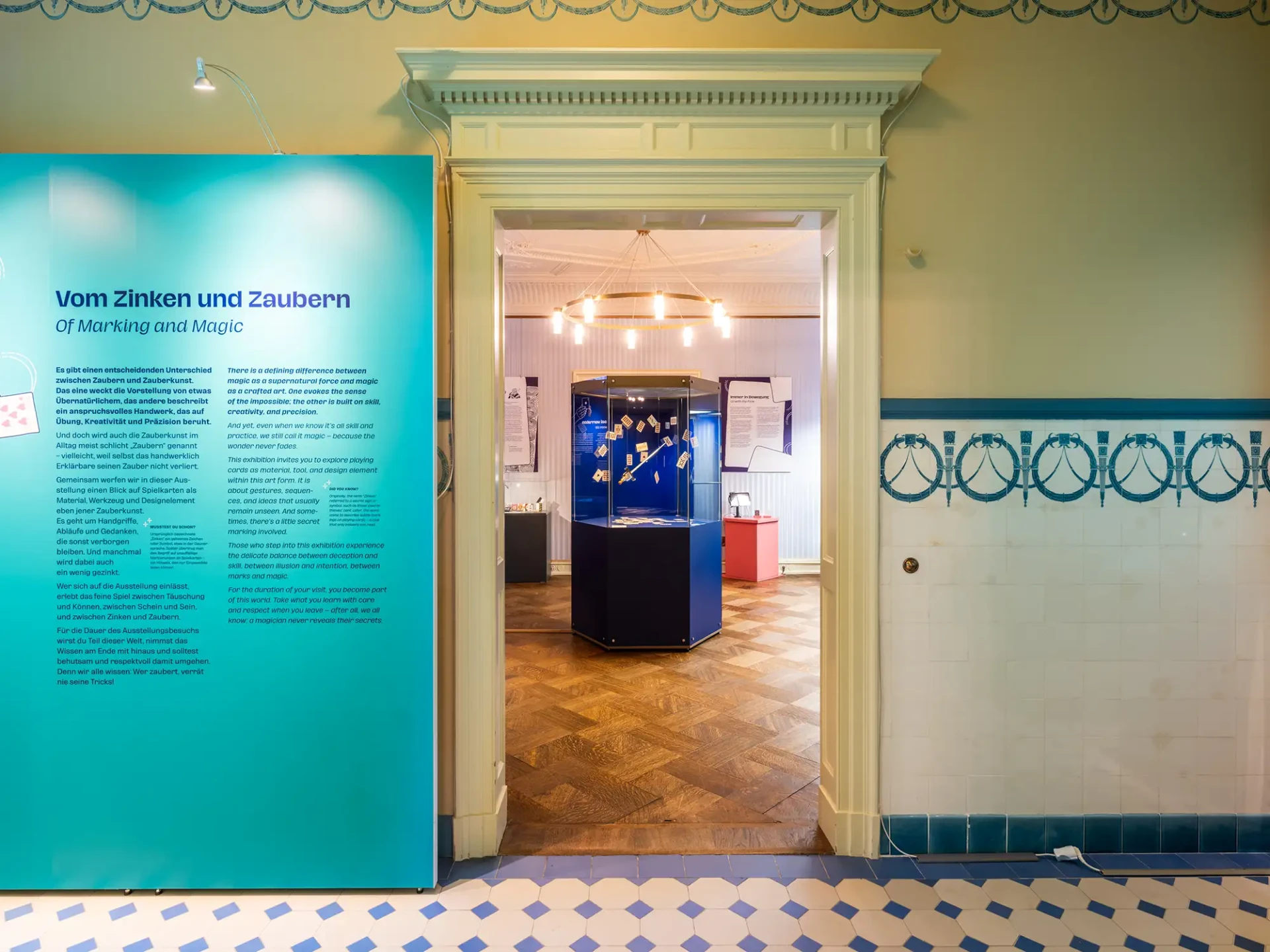 Blick aus dem ersten Ausstellungsraum in den zweiten Raum. In der Mitte des zweiten Raums steht eine Vitrine mit einem historischen Kartendegen.