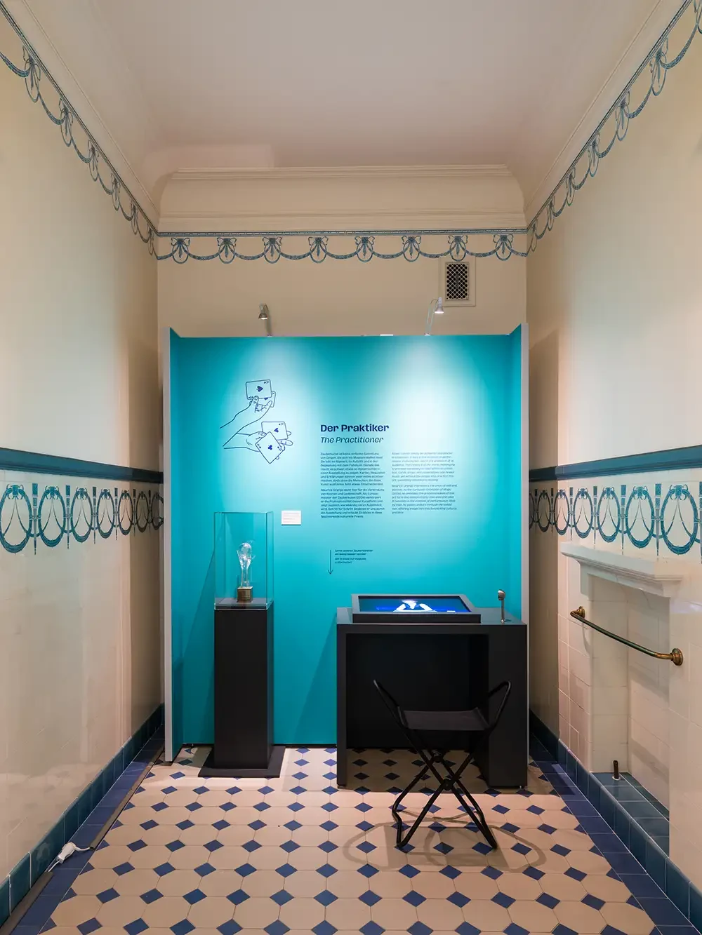 Blick nach rechts im ersten Ausstellungsraum. Vor einer Texttafel steht ein Pokal in einer Vitrine sowie ein Medientisch.