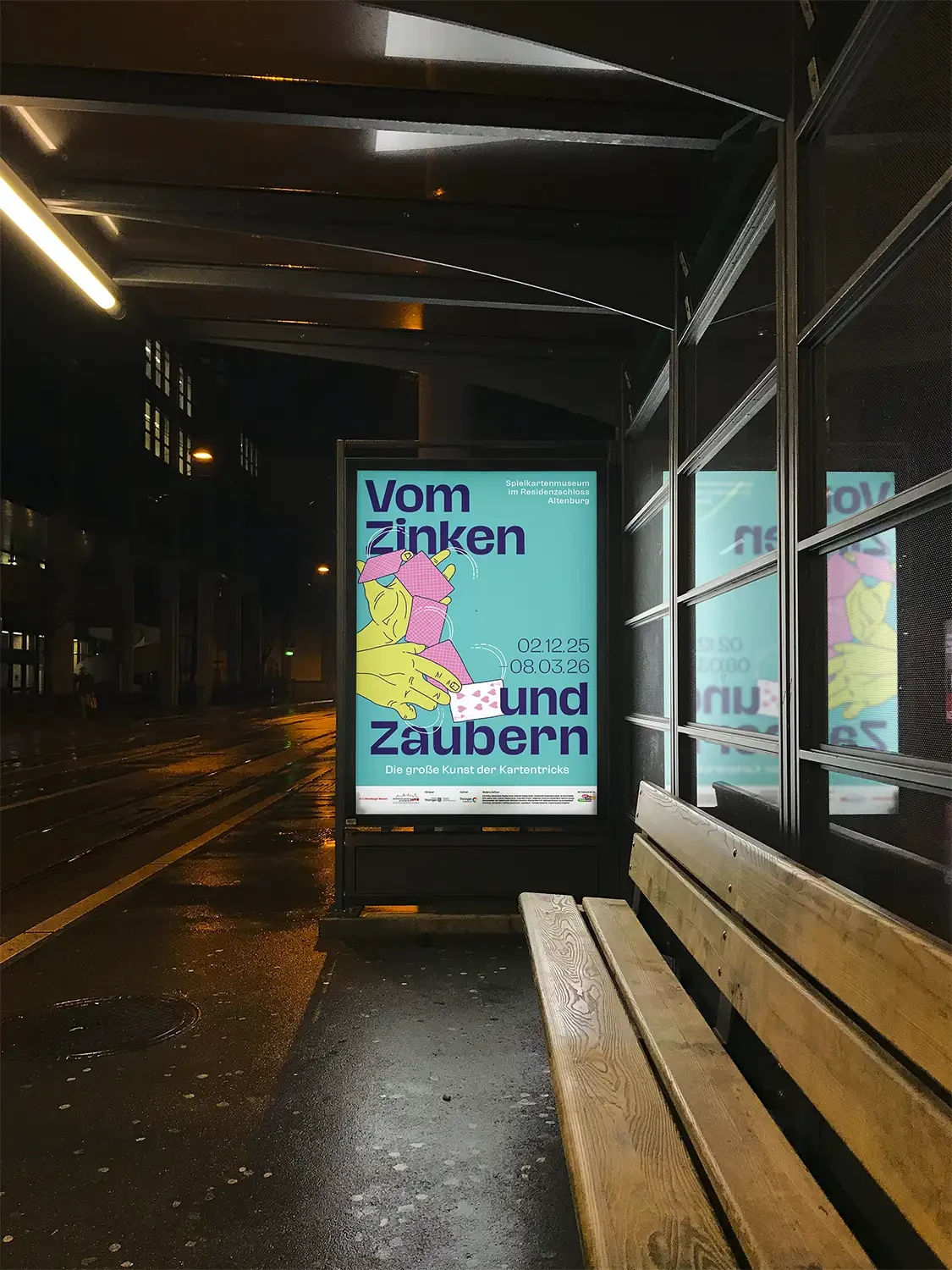 Beleuchtetes Ausstellungsplakat an einer Bushaltestelle.